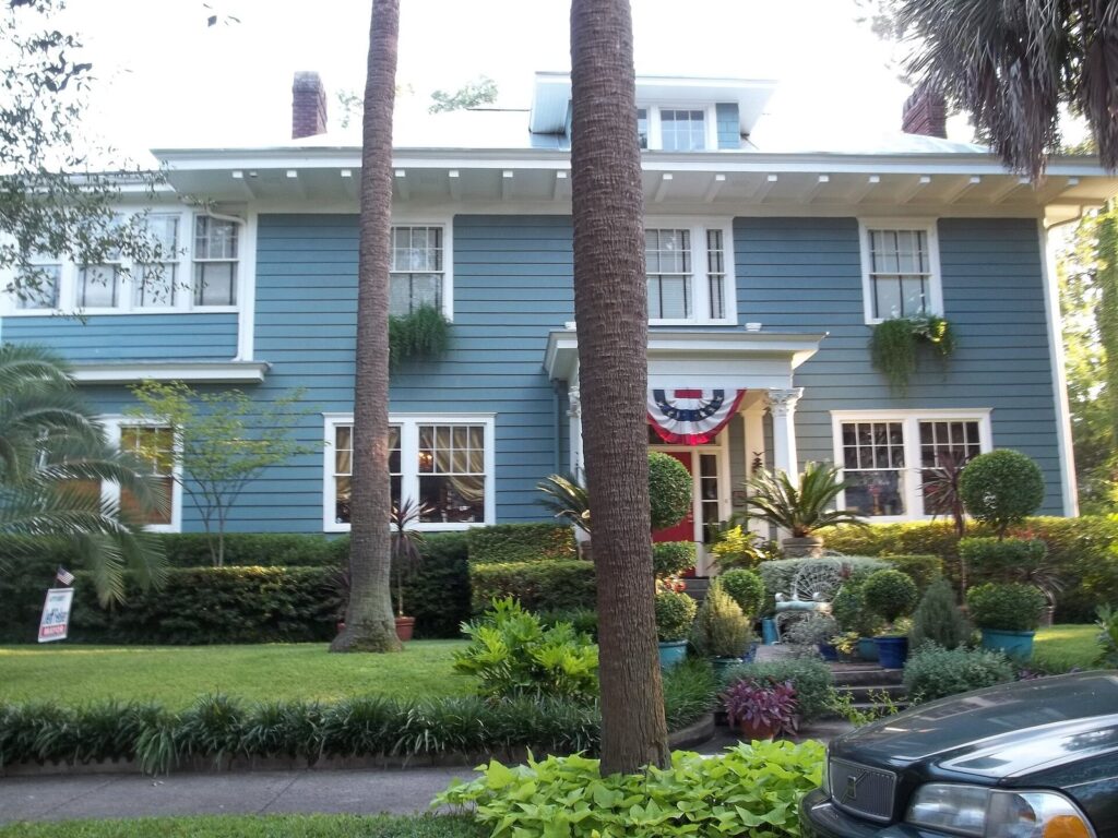 A blue two-story early-1900s house with a deep porch and palms in the Ardsley Park neighborhood