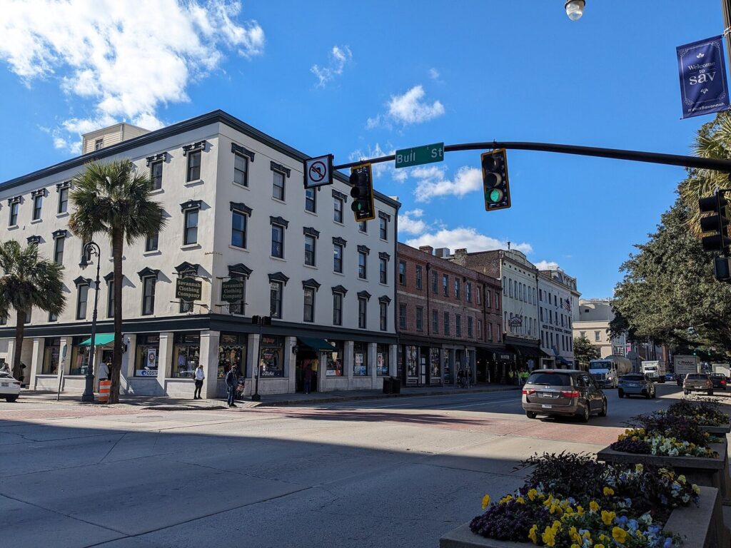 The corner of Bull Street and Bay Street in downtown Savannah, with traffic lights and historic buildings