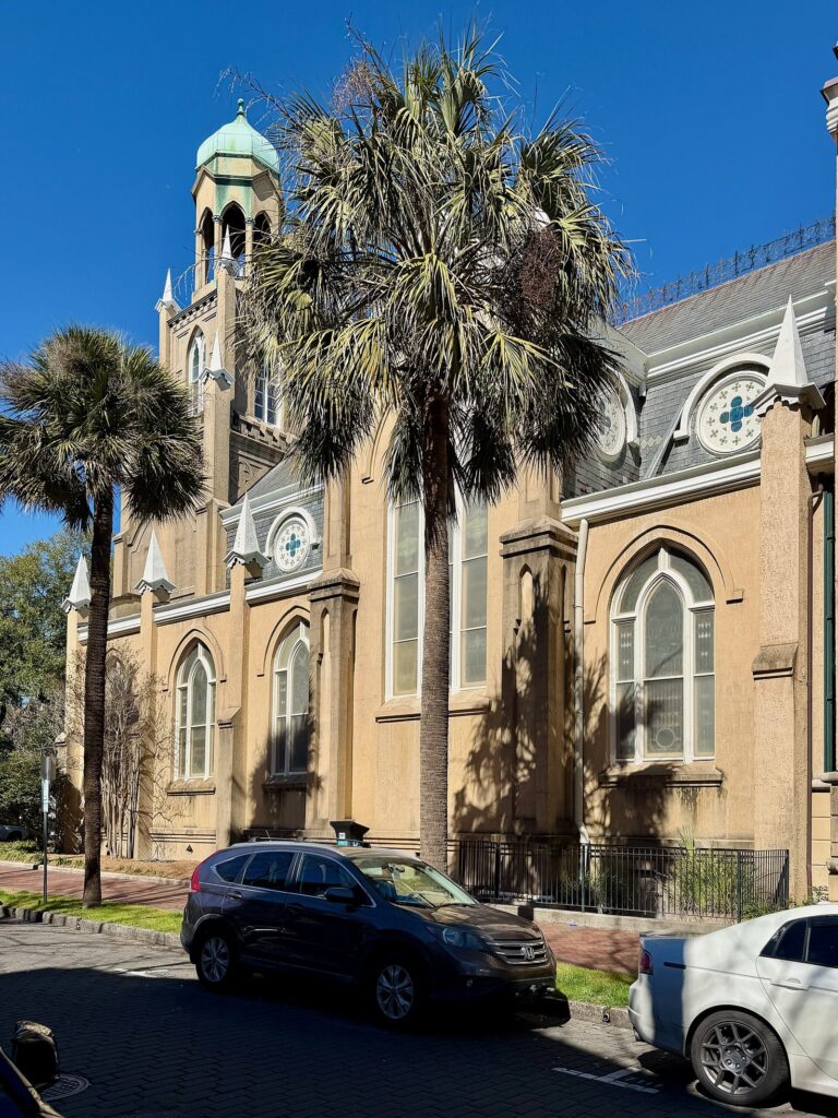 The Gothic Revival synagogue of Congregation Mickve Israel on Monterey Square, framed by palm trees under a blue sky