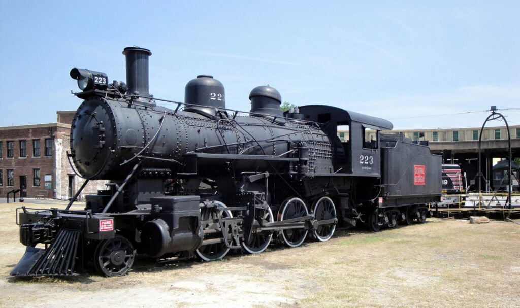 A black steam locomotive on display in the yard of the Georgia State Railroad Museum in Savannah