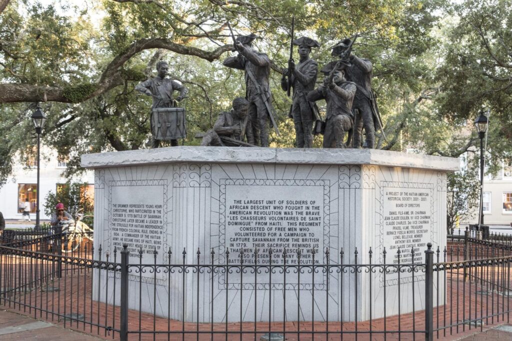 Bronze figures of soldiers and a drummer boy on the white stone base of the Haitian Monument in Franklin Square, Savannah