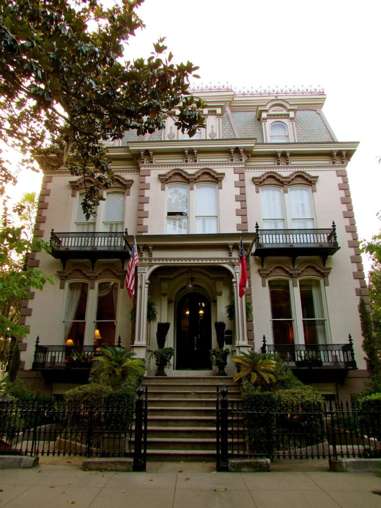 An ornate Second Empire mansion with iron balconies and a mansard roof facing Lafayette Square in Savannah