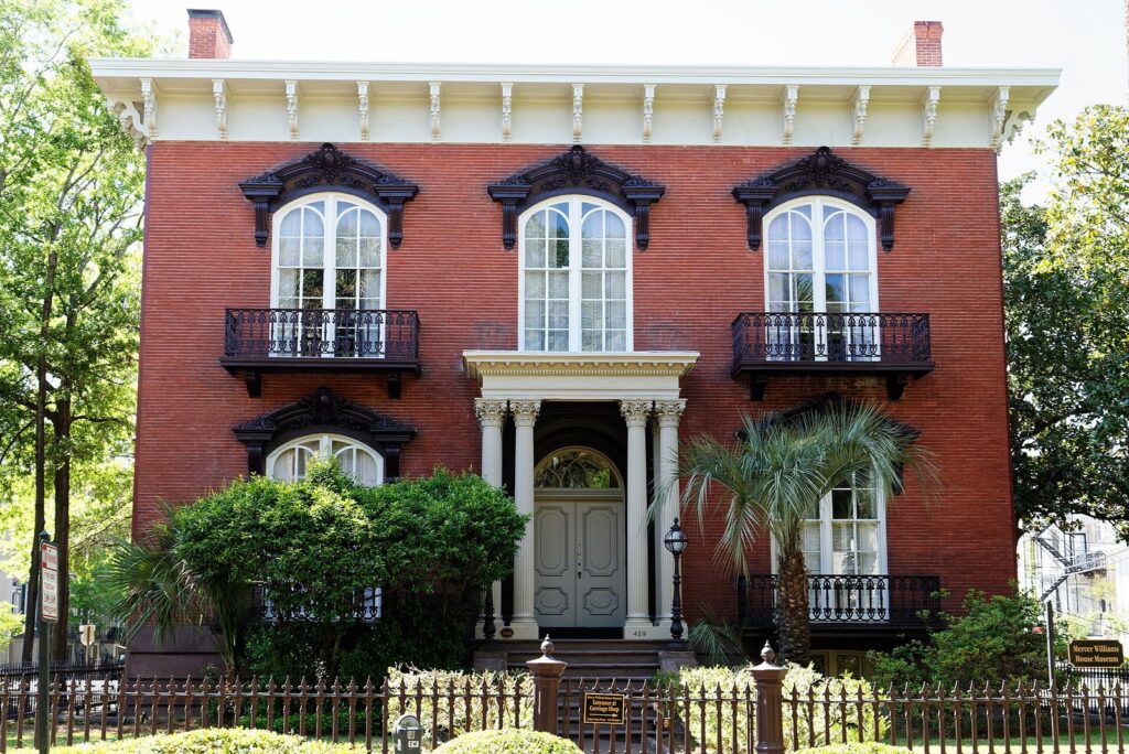 The red brick Mercer House with arched windows and iron balconies on Monterey Square in Savannah