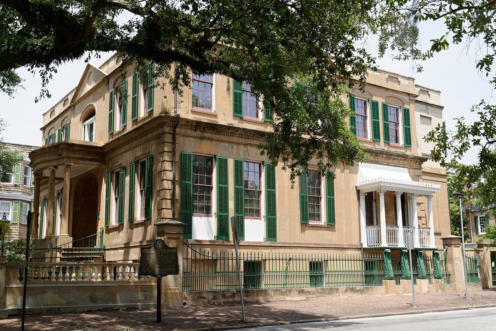 The ochre-stuccoed Regency facade of the Owens-Thomas House with green shutters and an iron-railed porch on Abercorn Street