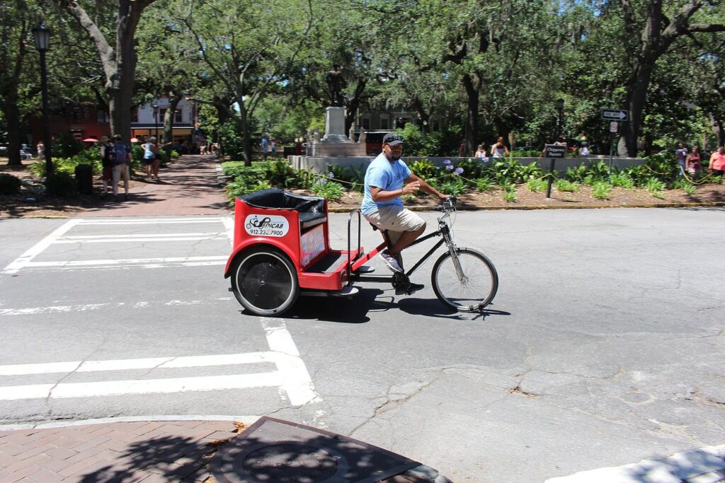 A pedicab driver pedals past the live oaks of Chippewa Square in downtown Savannah