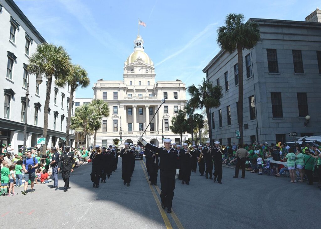 Best time to visit Savannah GA: a St. Patrick's Day parade marching band passes crowds in green in front of Savannah City Hall