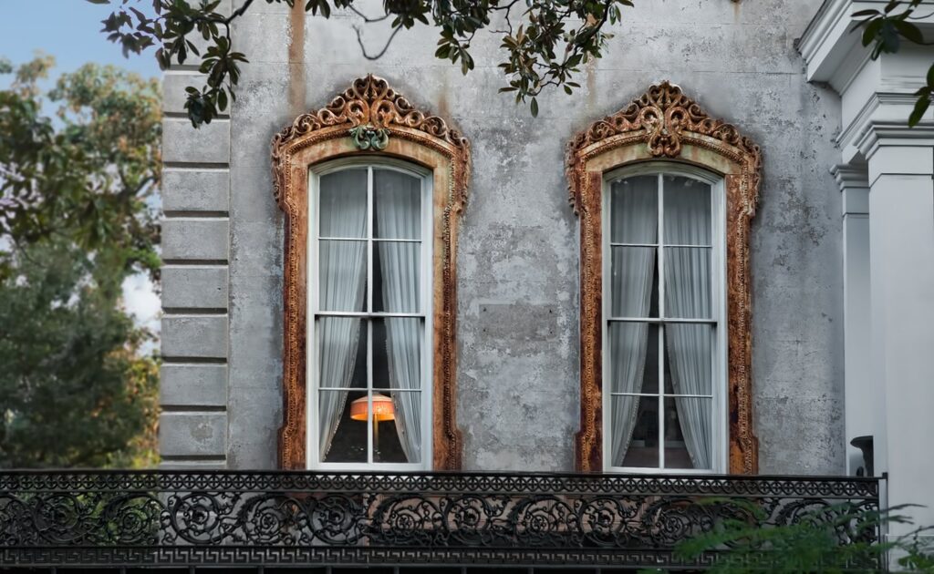 Ornate carved window frames and an iron balcony on a historic house in Savannah's Victorian District