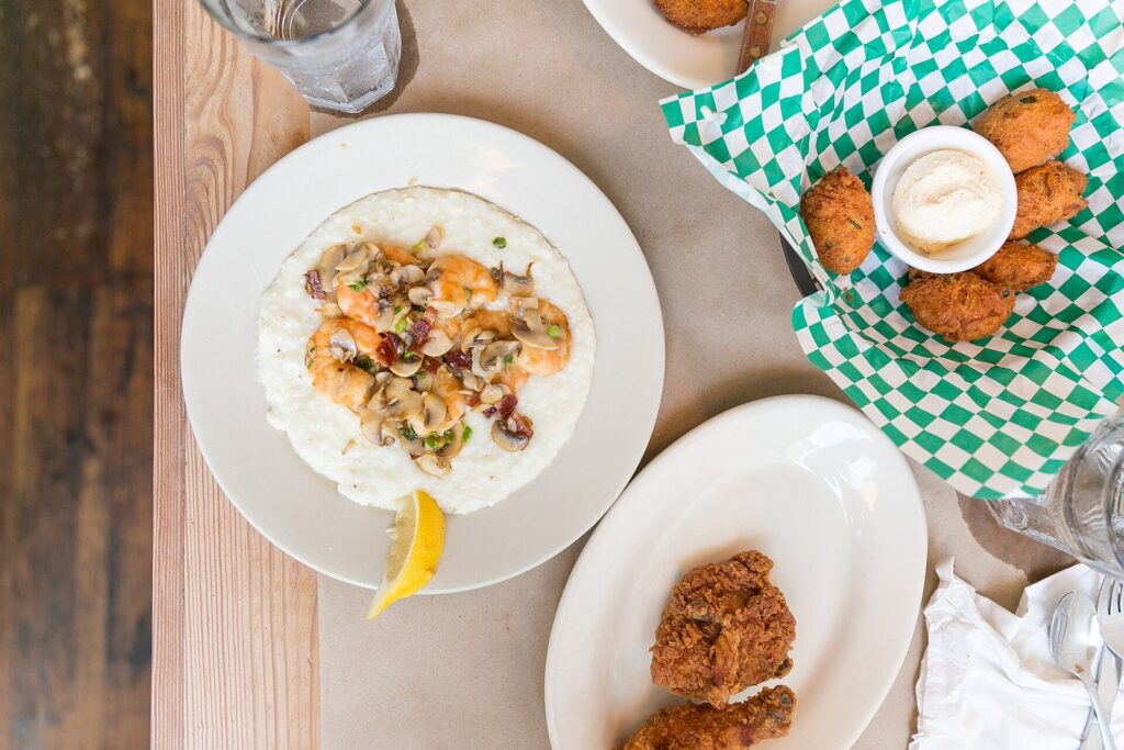 A plate of shrimp and grits topped with mushrooms and scallions, served with fried sides