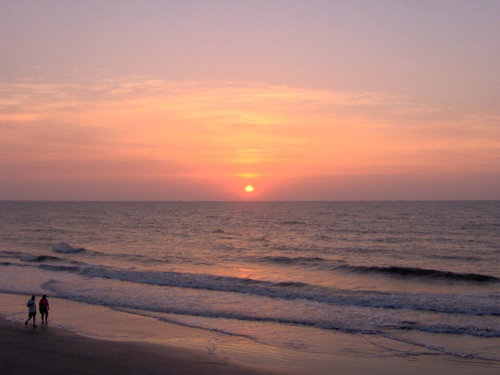 Tybee Island travel guide: two people walking the edge of the surf at sunrise on Tybee Island