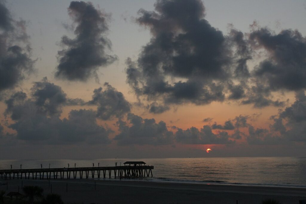 The Tybee pier silhouetted against a cloudy sunrise over the Atlantic