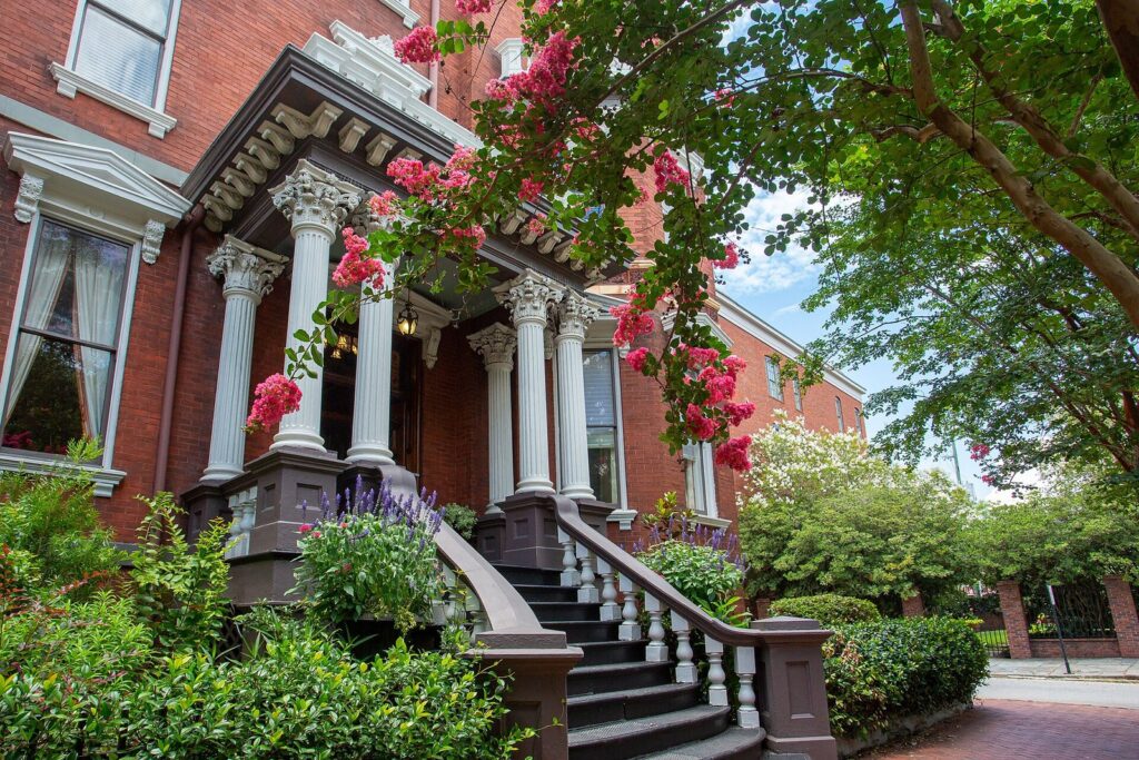 Where to stay in Savannah GA: the columned entrance of the Kehoe House inn framed by crepe myrtle blossoms