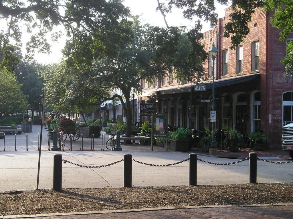 Outdoor tables, planters and red brick warehouses in the pedestrian courtyard of City Market, Savannah