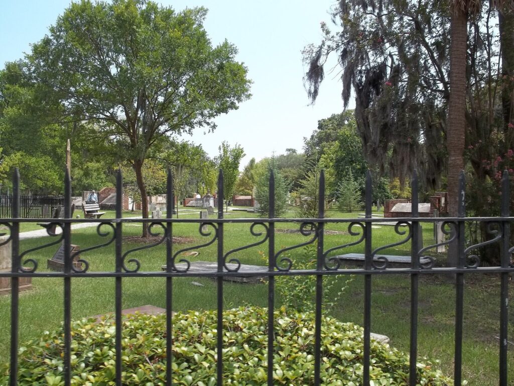 Box tombs and headstones seen through the black iron fence of Colonial Park Cemetery in Savannah