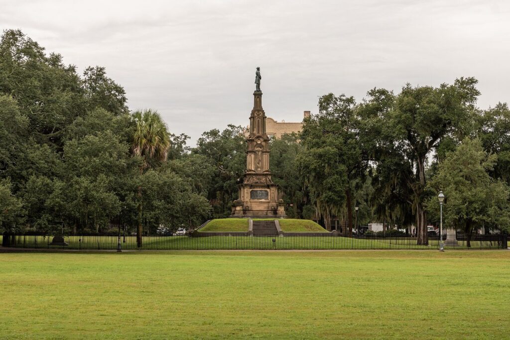 The tall sandstone Civil War memorial on a raised mound at the center of Forsyth Park, seen across a green lawn