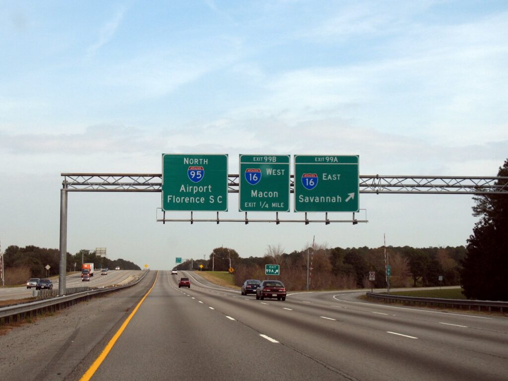 Overhead highway signs on I-95 near Savannah pointing north to the airport and east on I-16 to Savannah