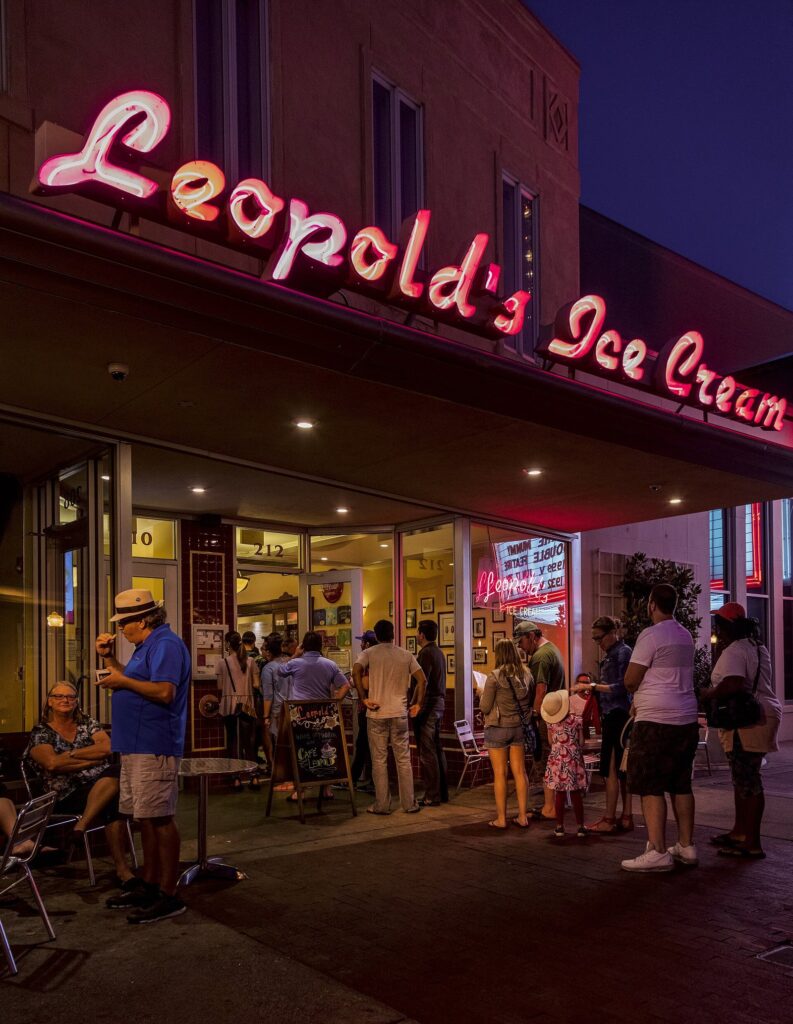 Red neon Leopold's Ice Cream sign glowing above customers lining up outside the shop on Broughton Street at night