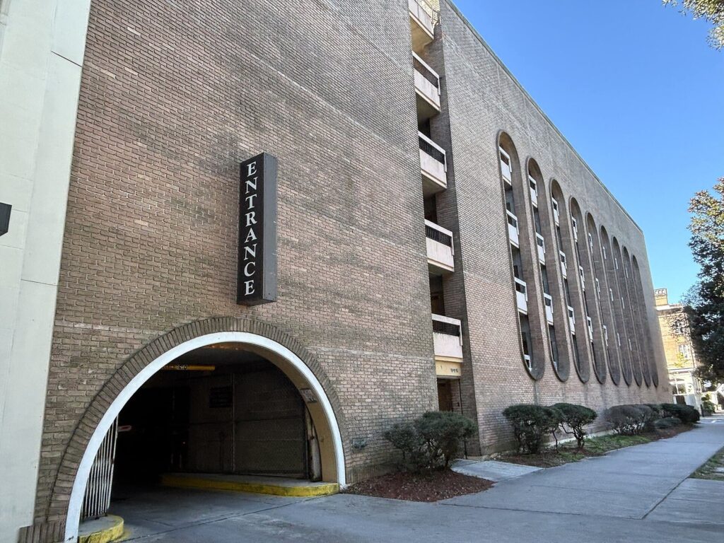 A tan brick parking garage with arched entrance and ribbon windows at Liberty and Whitaker streets in Savannah