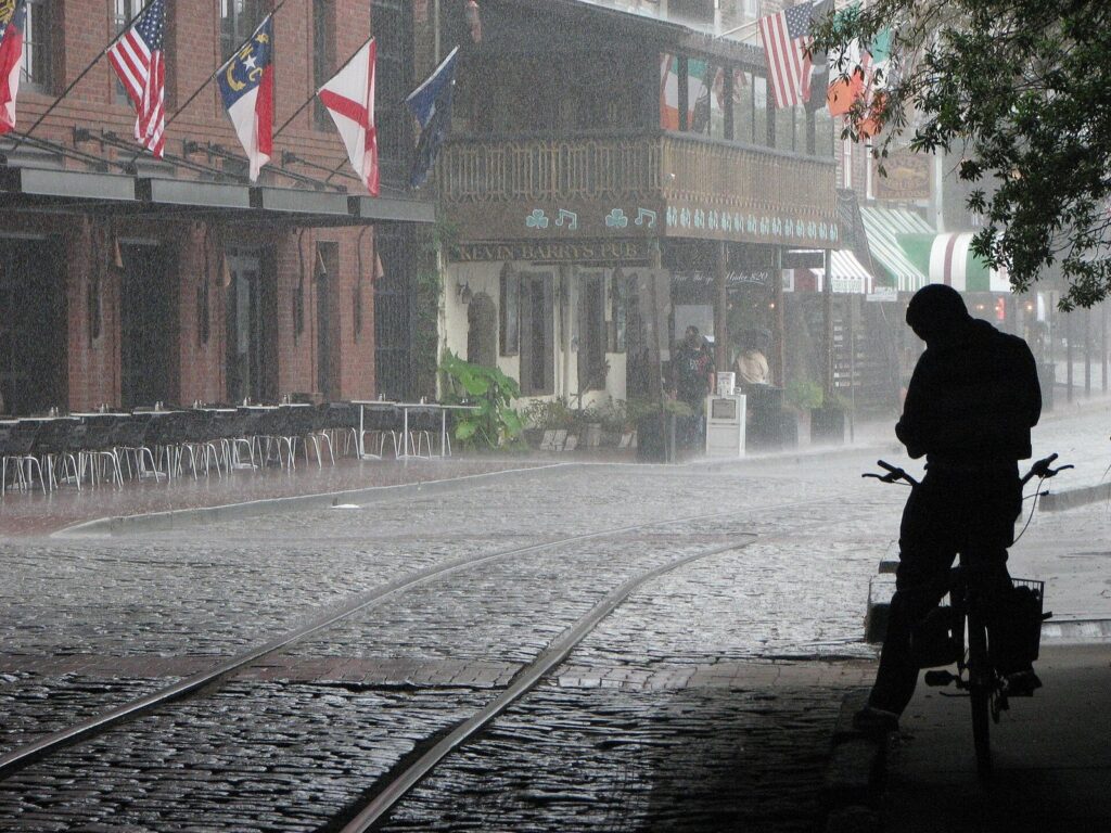 River Street visitor guide: a cyclist pauses in a downpour on River Street's cobblestones and old rail tracks in Savannah