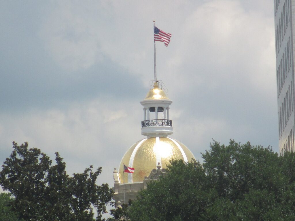 The gold-leafed dome and clock tower of Savannah City Hall rising above the trees on Bay Street